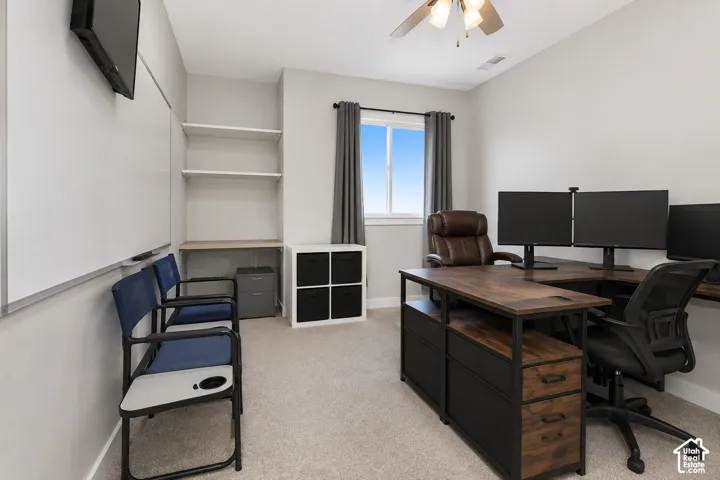 Room featuring neutral wall tones, carpeted flooring, a ceiling-mounted fan with light fixture, a single window, and built-in shelving