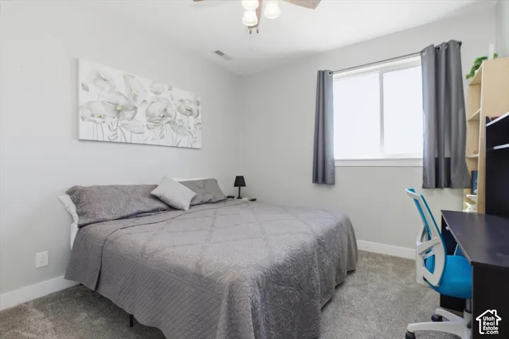 Neutral interior featuring grey carpeting, light-toned wall paint, a sliding window, and a ceiling-mounted light fixture with a fan