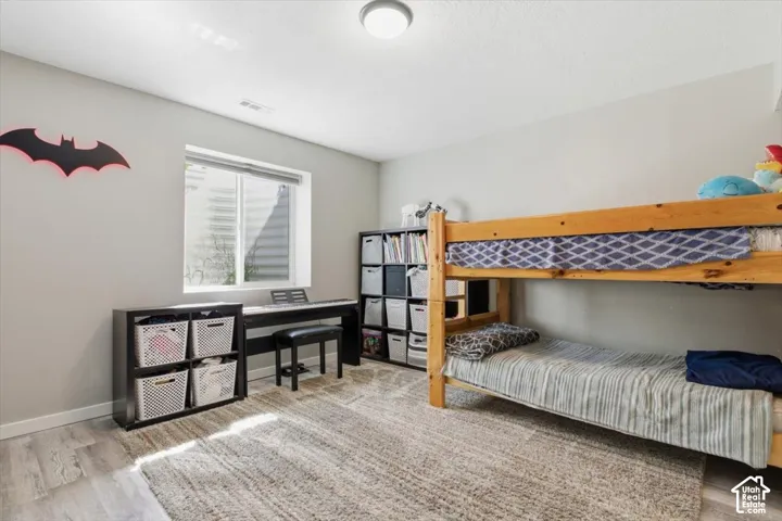 Neutral-toned room featuring wood-finish flooring, a single-pane window, and a central ceiling light fixture
