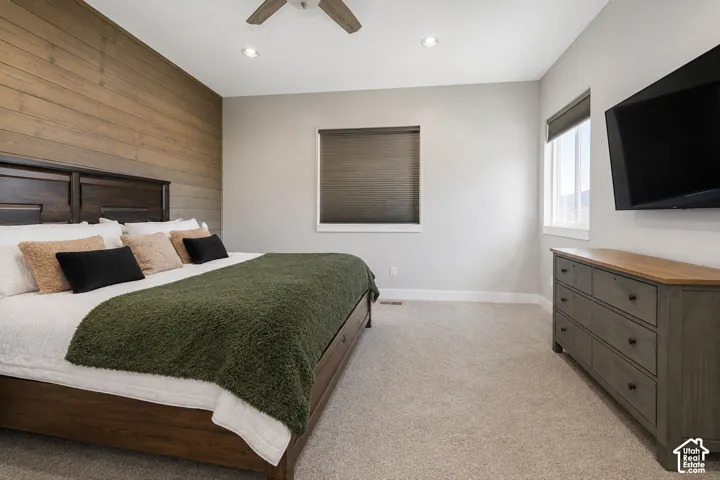 Bedroom featuring a horizontal wood-plank accent wall, neutral carpeting, recessed ceiling lighting, and a ceiling fan