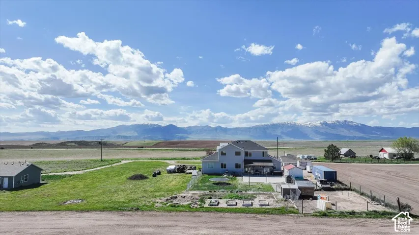 Two-story residence featuring a paved patio, fenced grounds, and expansive mountain terrain