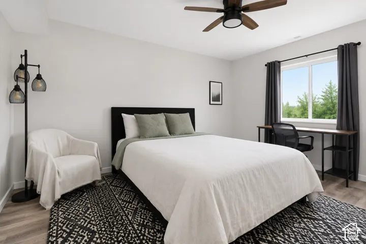 Neutral-toned interior featuring wood-finish flooring, a ceiling fan with integrated lighting, and a large window