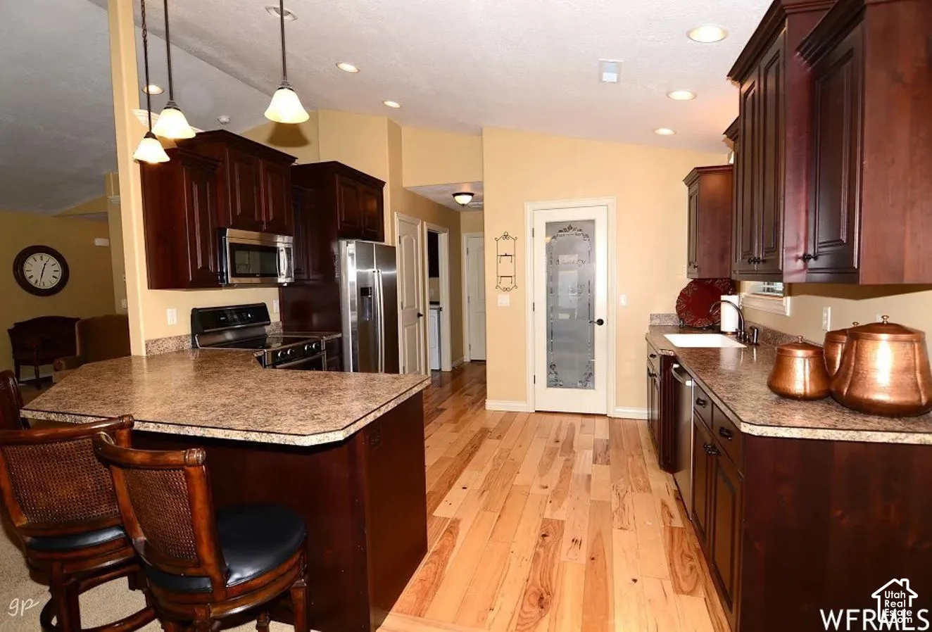 Kitchen featuring dark wood cabinetry, wood-finish flooring, a patterned countertop, recessed lighting, and a pantry with a decorative glass-paneled door