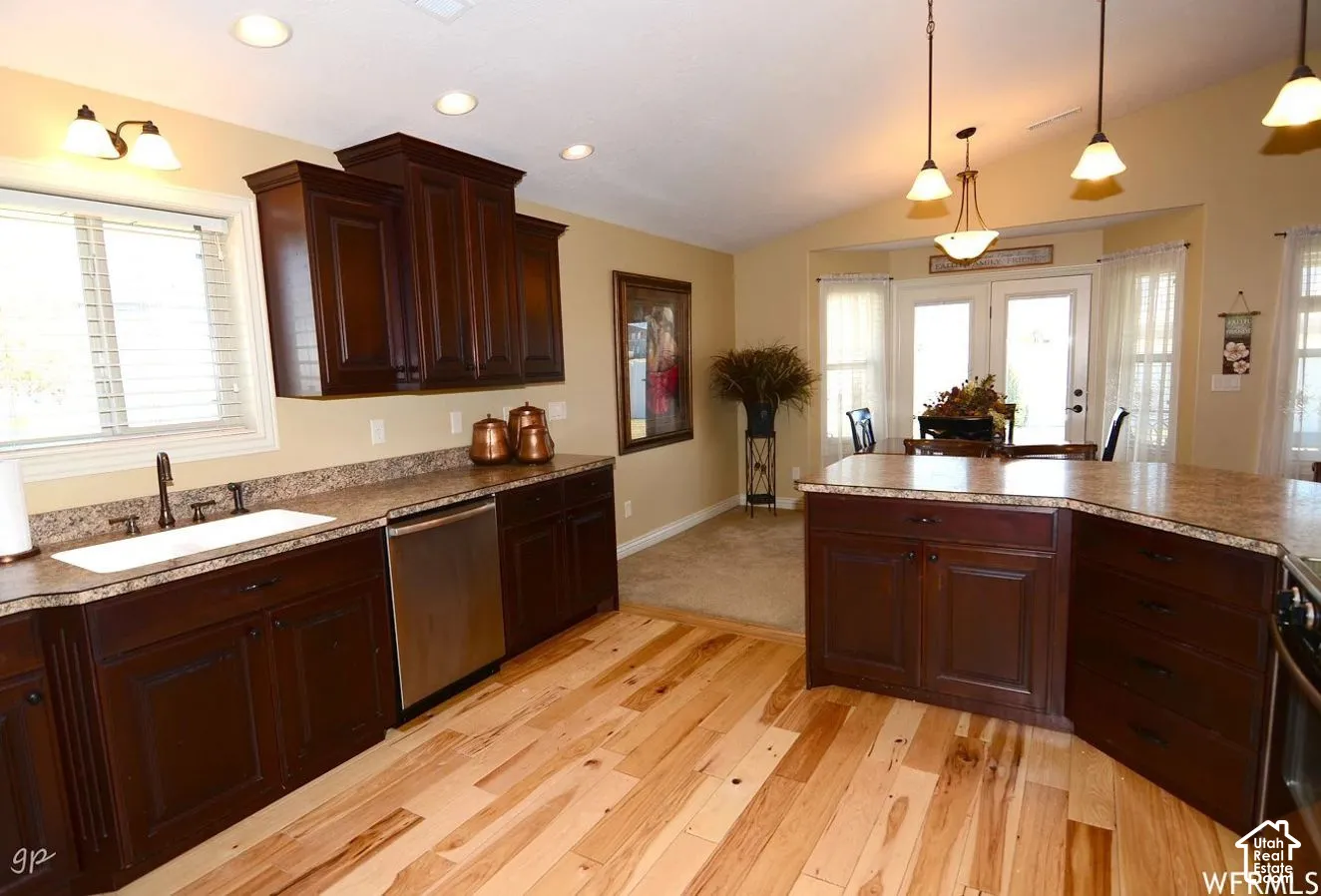 Kitchen featuring dark wood cabinetry, solid surface countertops, wood-finish flooring, stainless steel dishwasher, and recessed lighting