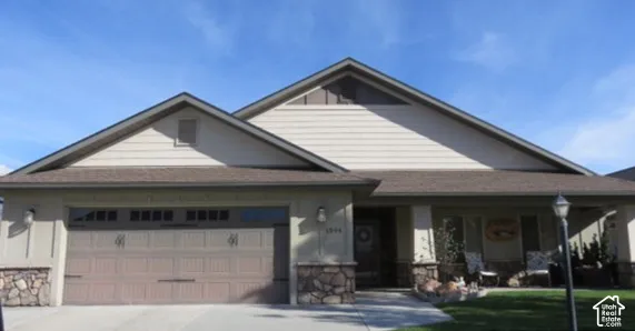 Exterior featuring a neutral-toned stucco facade, stone veneer accents, multi-gabled roofline, horizontal siding in the gables, and an attached two-car garage