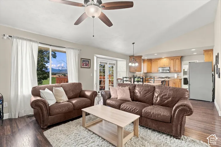 Vaulted ceilings, wood-finish flooring, recessed lighting, ceiling fan with integrated light fixture, and French doors leading to exterior space