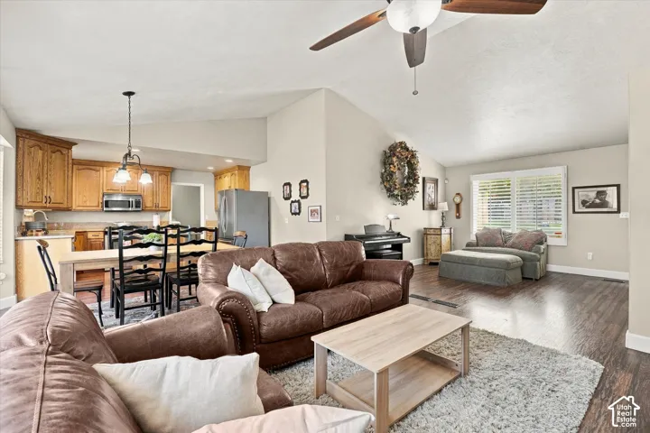 Open-concept interior featuring vaulted ceilings, wood-finish flooring, wood cabinetry, and a ceiling fan with integrated lighting