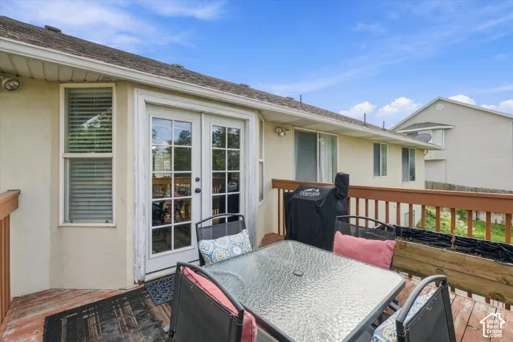 Exterior wooden deck featuring a perimeter railing and glass-paned double doors
