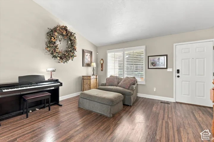 Interior space featuring vaulted ceilings, wood-finish flooring, and window shutters