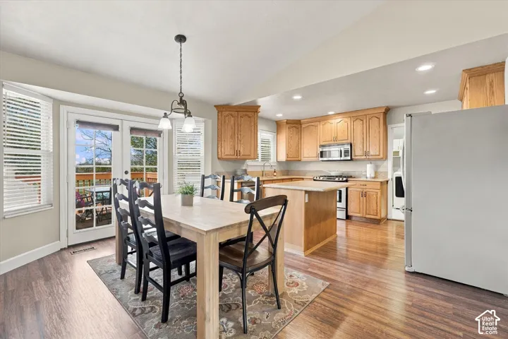 Kitchen featuring wood-finish cabinetry, an island with a countertop, recessed lighting, wood-finish flooring, and double glass-paned doors