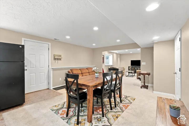 Open-concept interior featuring recessed lighting, neutral wall paint, carpeting, and a built-in black refrigerator