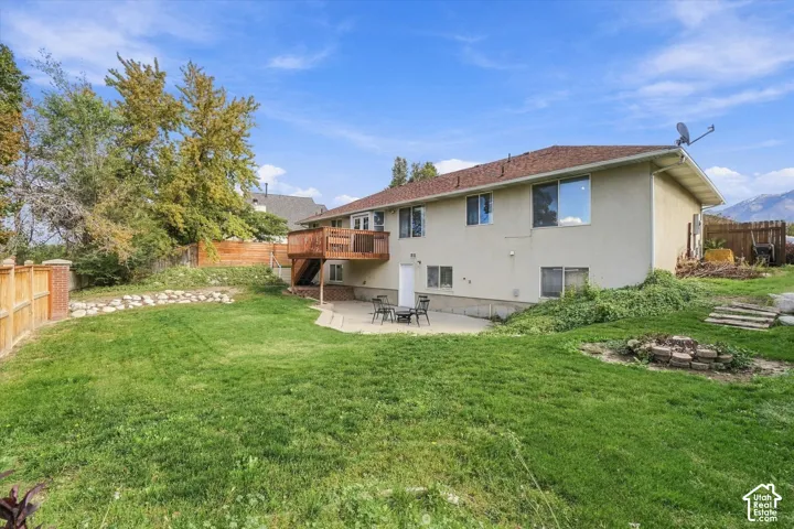 Exterior backyard featuring a concrete patio, elevated wood deck, and wood perimeter fencing