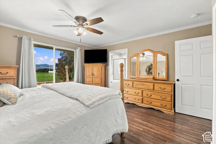 Bedroom featuring wood-finish flooring, a ceiling fan with integrated lighting, sliding glass doors, and a six-panel interior door