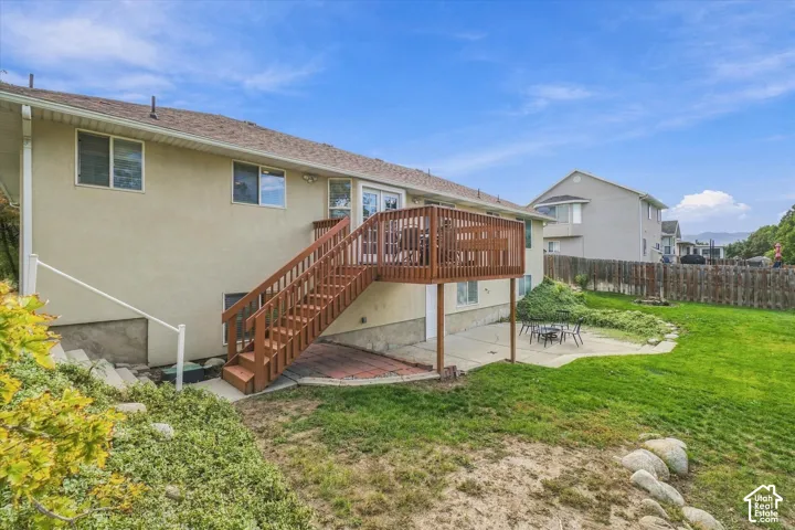 Rear exterior featuring a wood deck with stairs, a concrete patio, and a fenced yard