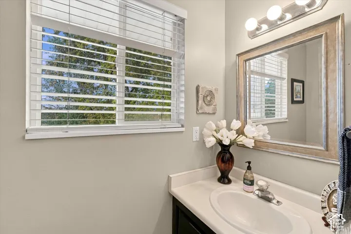 Bathroom vanity with a crisp white countertop, integrated basin, dark cabinetry, and a framed mirror accented by a multi-bulb vanity light fixture