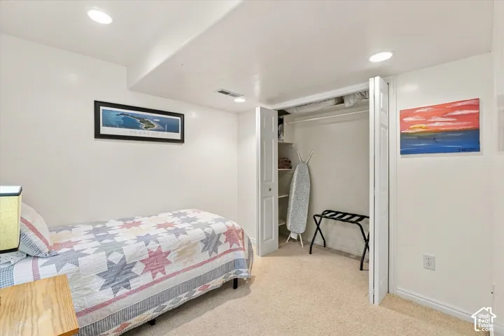 Neutral-toned carpeting, recessed ceiling lighting, and a closet featuring bi-fold doors and integrated shelving