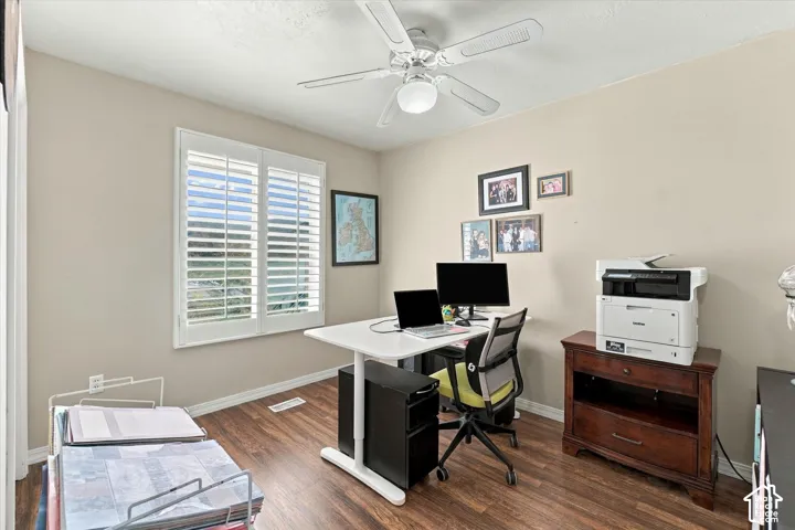 Wood-finish flooring, white plantation shutters, and a ceiling-mounted light fixture with a fan