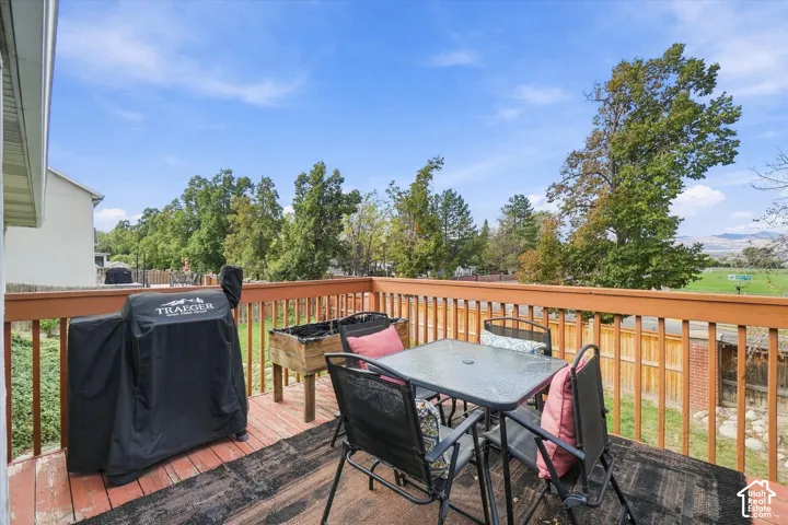 Elevated wooden deck with balustrade railings and mature tree line