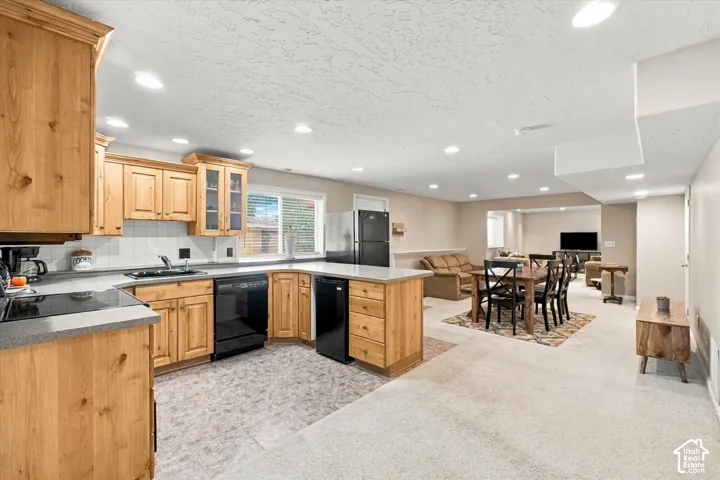 Kitchen featuring natural wood cabinetry, solid surface countertops, recessed lighting, and black appliances