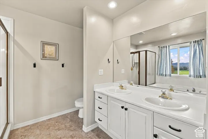 Dual-sink vanity with white cabinetry and solid surface countertop, large wall-to-wall vanity mirror, recessed lighting, and tile flooring