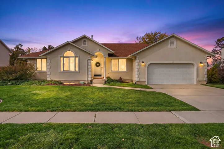Stucco exterior featuring arched windows, stone corner accents, a covered entryway, and an attached two-car garage