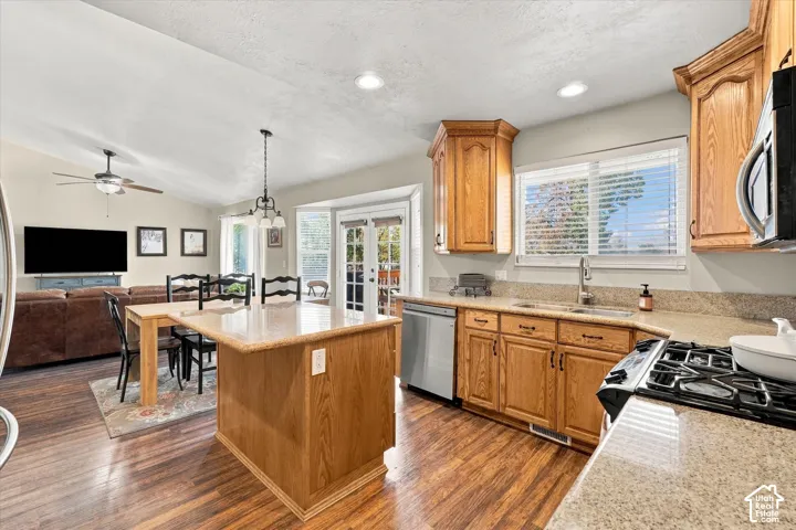 Kitchen featuring custom wood cabinetry, an island with countertop seating, stone-finish countertops, wood-finish flooring, and a glass-paneled door