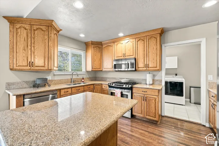Kitchen featuring wood cabinetry, stone-surface countertops, a center island, stainless steel appliances, and recessed lighting