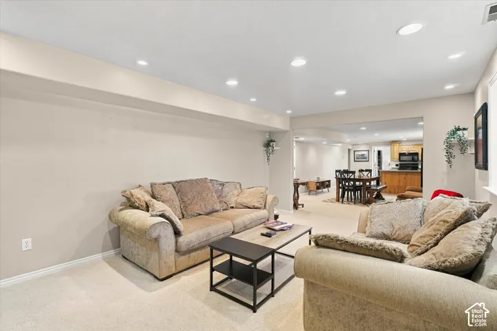 Neutral interior space featuring recessed ceiling lighting, carpeted flooring, and a drop-beam ceiling structure