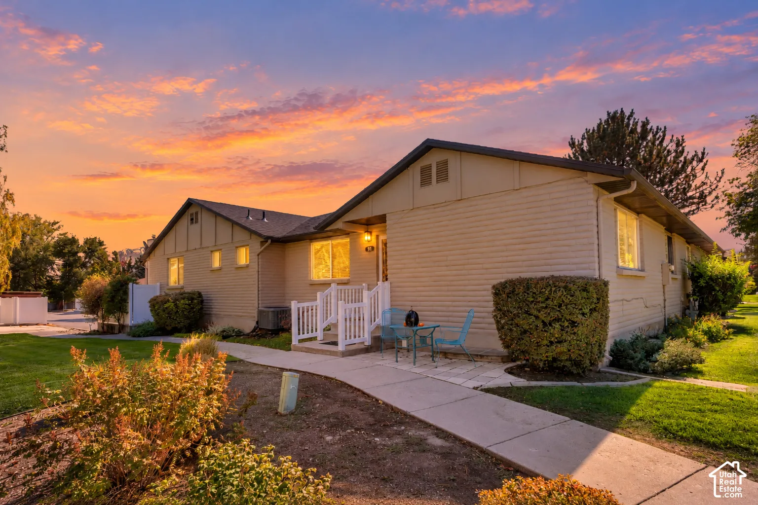 Rambler-style exterior featuring horizontal siding, a gabled roofline, a concrete walkway, and white wooden railing