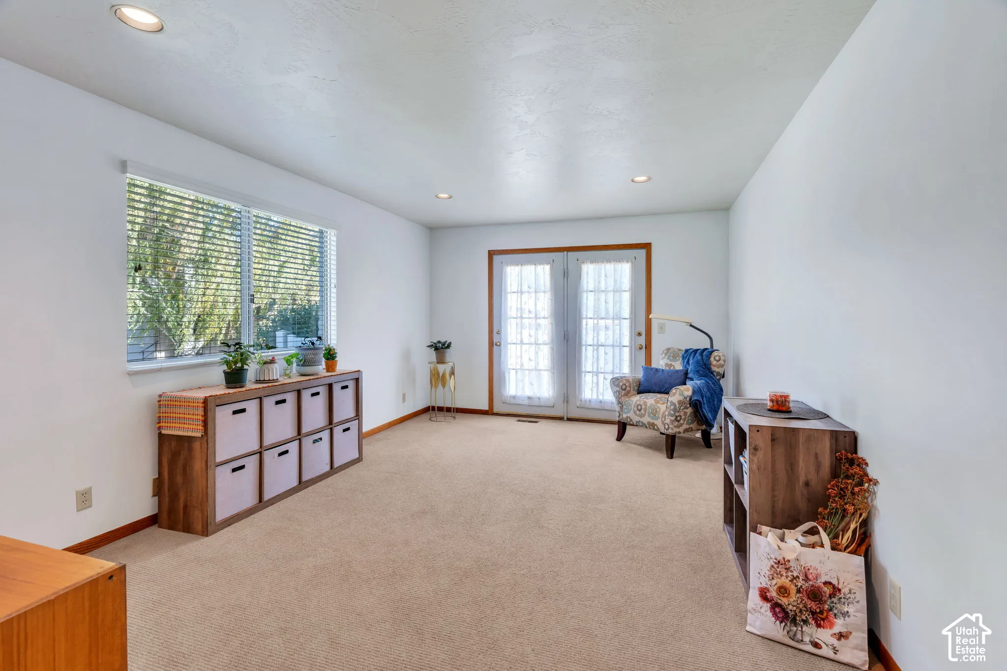 Neutral-toned carpeted flooring, recessed ceiling lighting, and double glass-paneled exterior doors with wood-finish trim