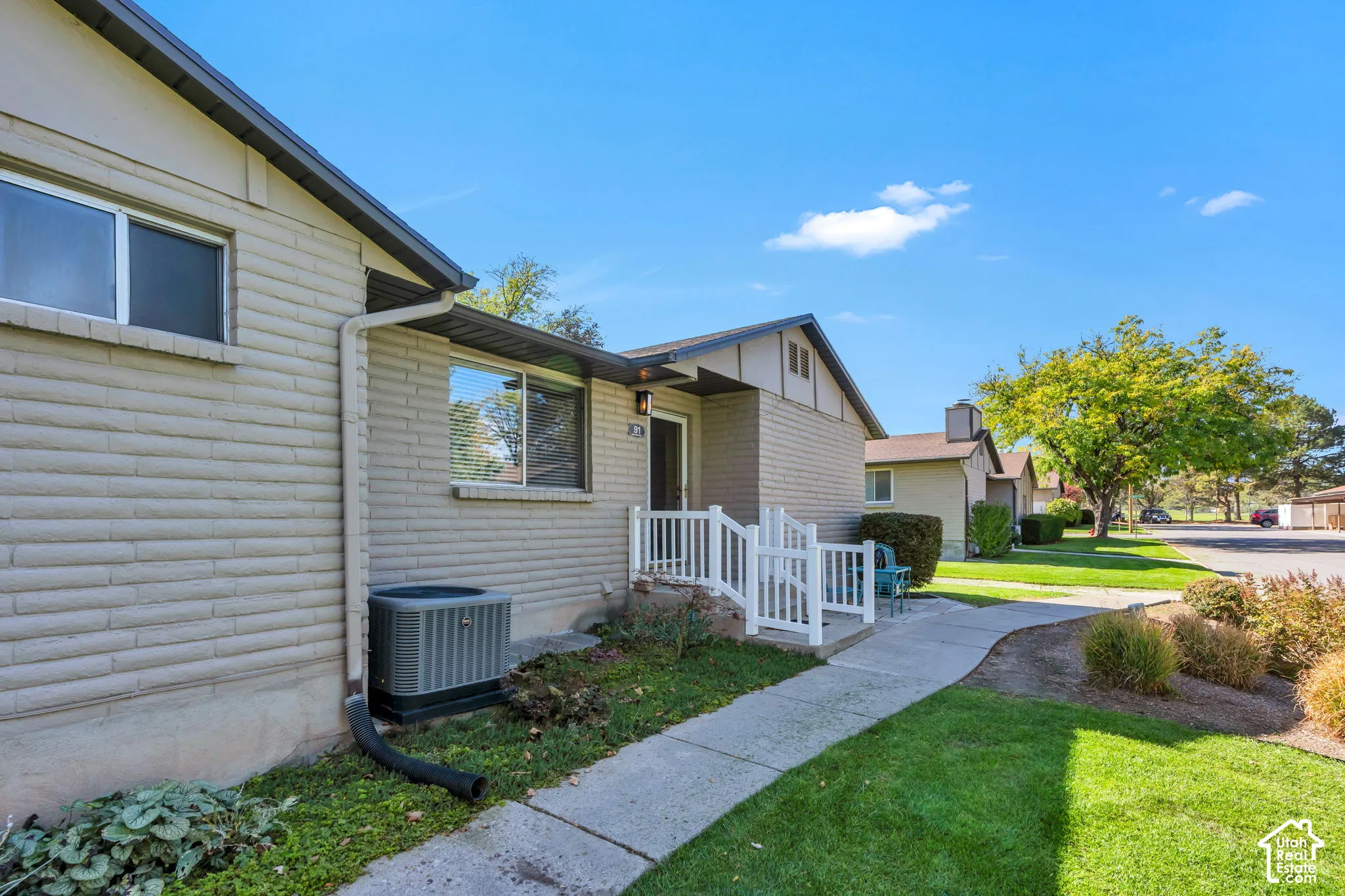 Exterior featuring horizontal masonry siding, concrete walkway, white-painted porch railing, and dual-pane windows