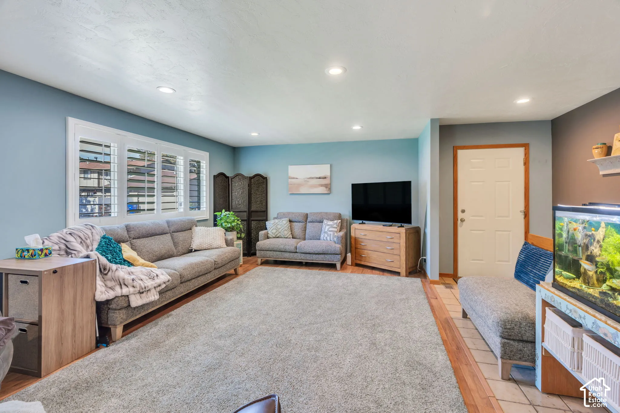 Living space featuring recessed lighting, multi-panel window with plantation shutters, and wood-finish flooring