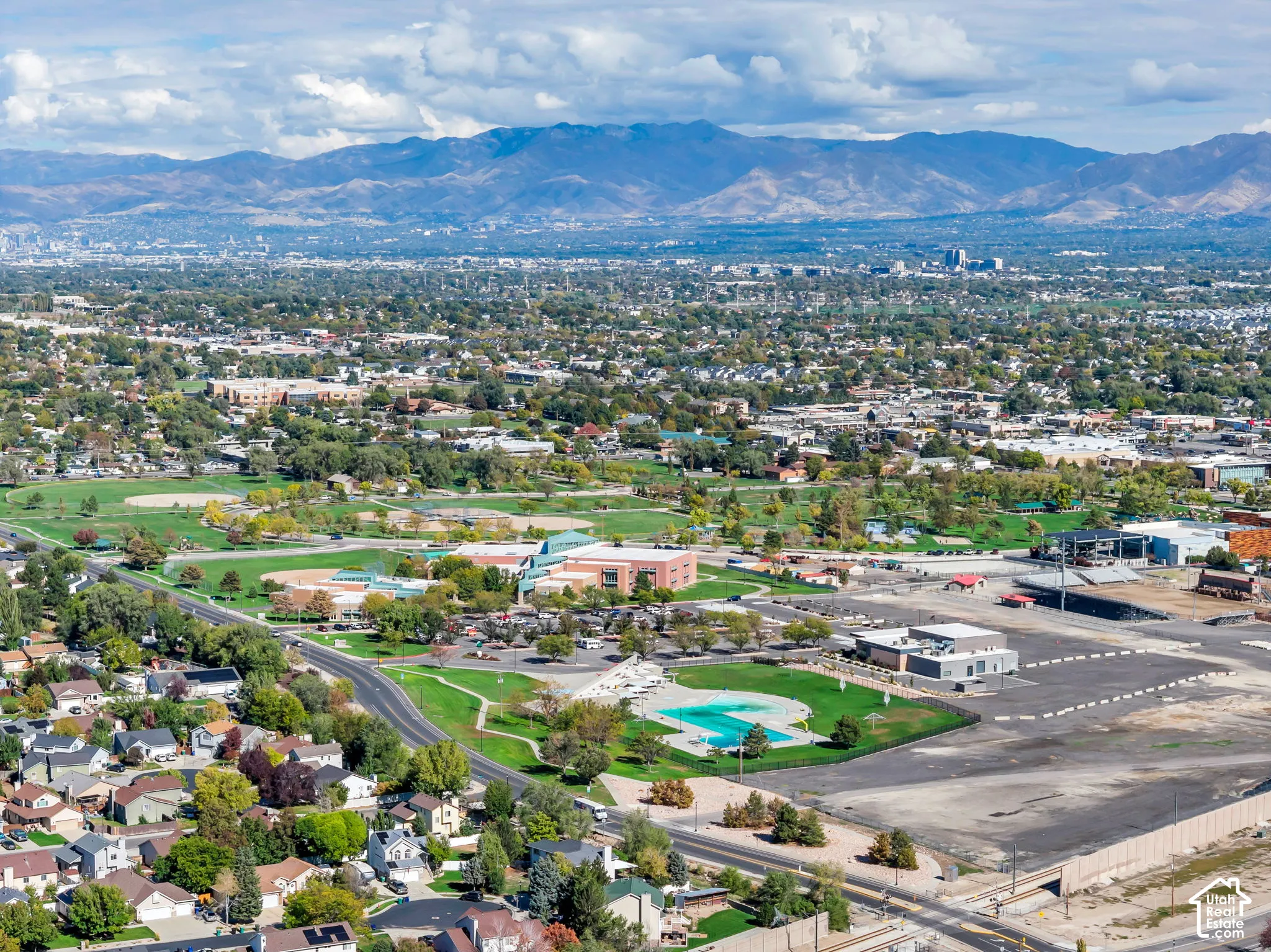 Aerial perspective featuring a prominent mountain backdrop, sprawling municipal park grounds, baseball fields, and a community swimming pool