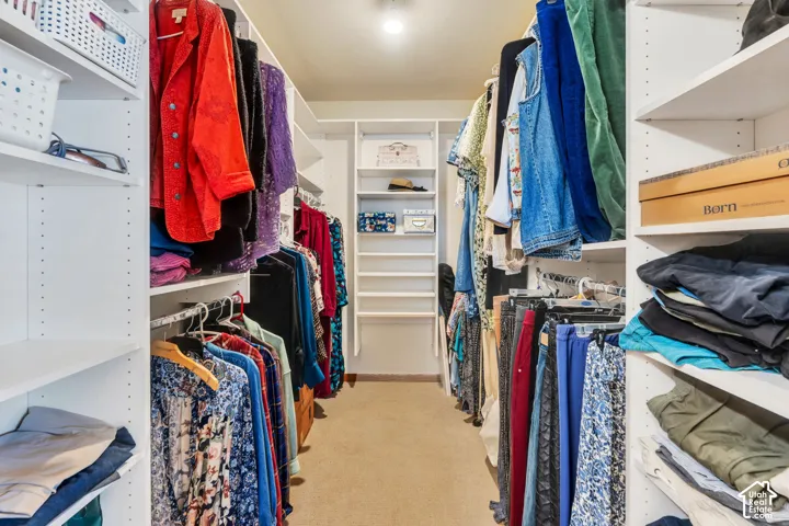 Walk-in closet featuring white built-in shelving, multiple hanging rods, and an overhead lighting fixture