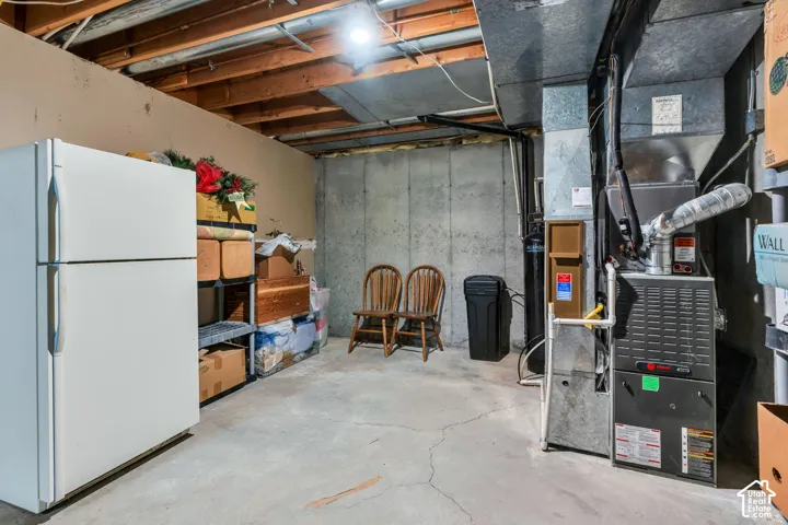 Utility area featuring a concrete floor, exposed wooden ceiling joists, poured concrete walls, and a dedicated furnace system