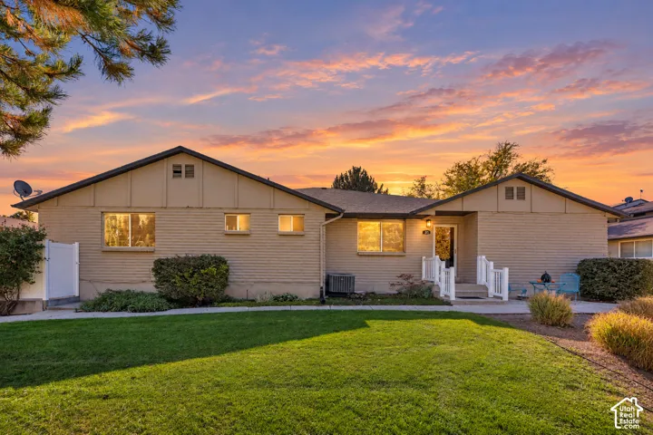 Single-story residence featuring a brick and panel exterior, low-pitch roofline, manicured lawn, and white picket porch railing