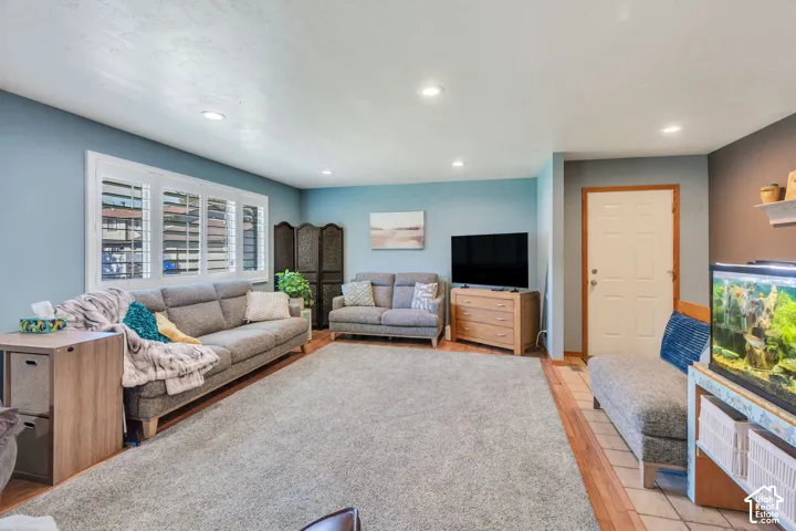 Living space featuring recessed lighting, multi-panel window with plantation shutters, and wood-finish flooring