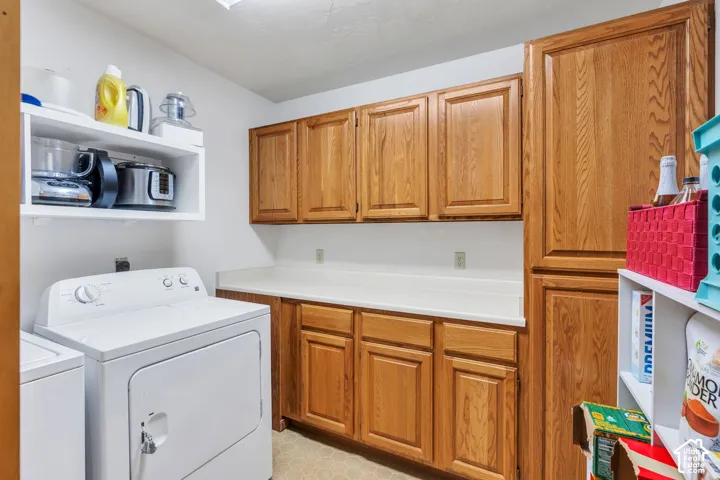 Utility room featuring wood-finish cabinetry, solid-surface countertop, floor-to-ceiling pantry storage, and fixed open shelving