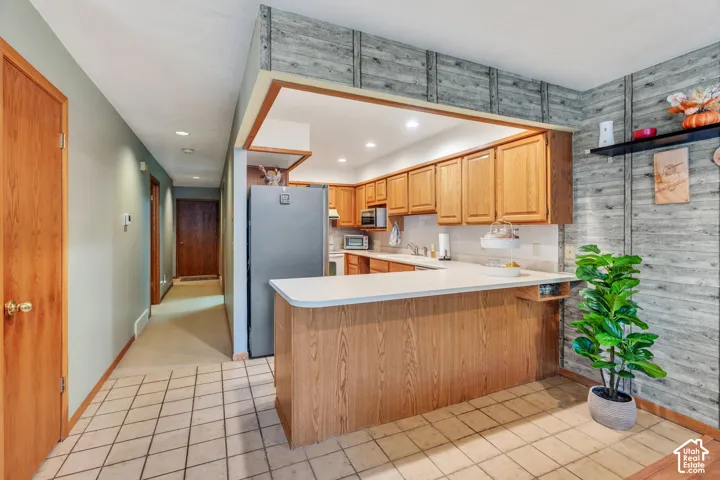 Kitchen featuring wooden cabinetry, a peninsula with a countertop, recessed lighting, and tile flooring