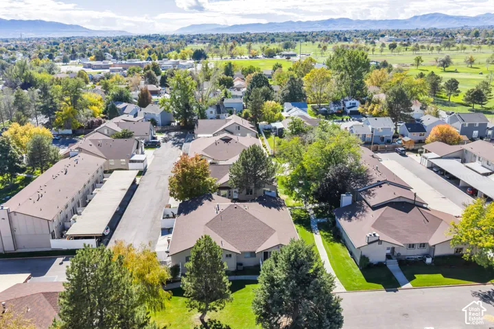 Aerial perspective showcasing residential structures with asphalt shingle roofing, integrated carport parking, mature landscaping, and mountain scenery in the distance