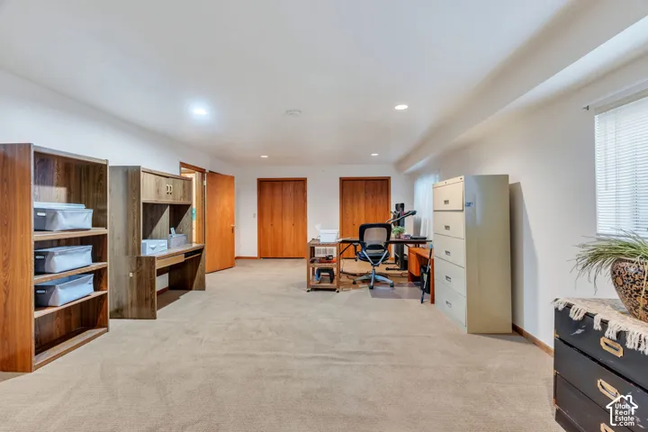 Spacious room featuring neutral carpeting, recessed lighting, and two sets of wood-finish closet doors