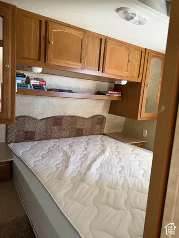 Wood-finish upper cabinetry, integrated shelving, flush-mount lighting, and bedside surfaces