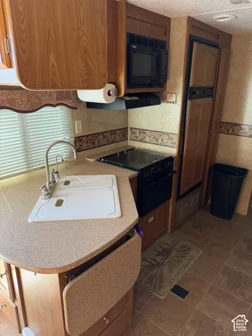Kitchen featuring wood-finish cabinetry, solid-surface countertops, integrated cooktop with oven, built-in microwave, and high-arc faucet