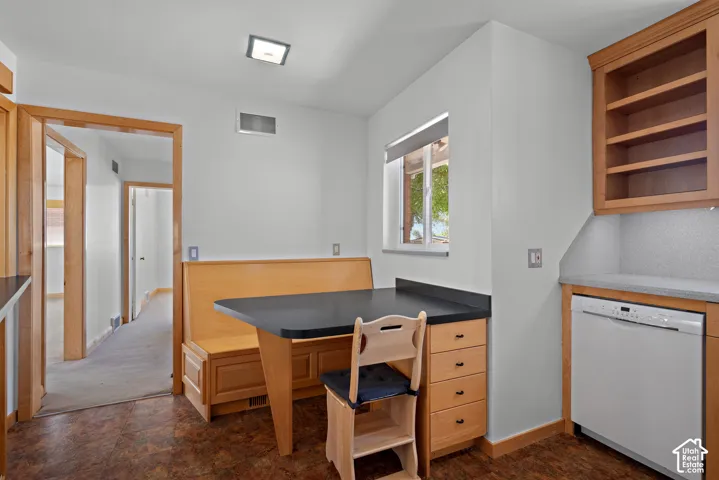 Built-in wooden dining nook with integrated seating, stone-finish countertops, natural wood cabinetry, and an under-counter dishwasher