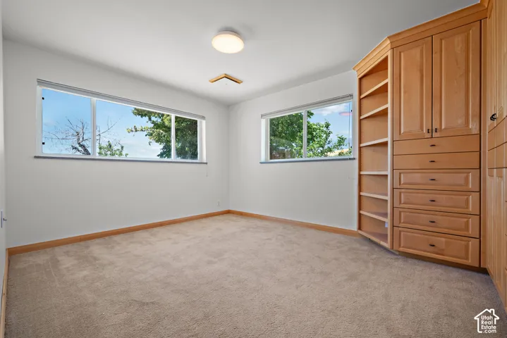 Room featuring built-in floor-to-ceiling cabinetry with shelving and integrated drawers, neutral carpeting, and horizontal sliding windows