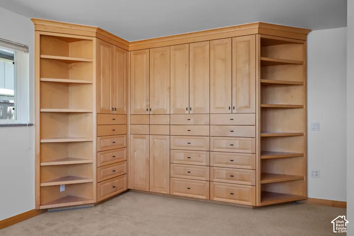 Custom light-toned wood cabinetry featuring extensive drawer storage, integrated corner shelving, crown molding, and recessed hardware
