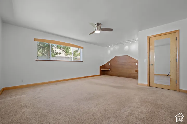 Custom wood-paneled feature wall with integrated floating nightstands, ceiling fan with light kit, recessed track lighting, and a solid-wood door featuring a full-length mirror inlay
