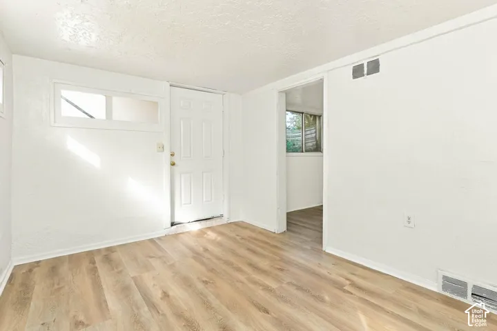 Room featuring wood-finish flooring, white walls, a horizontal transom window, and a paneled entry door