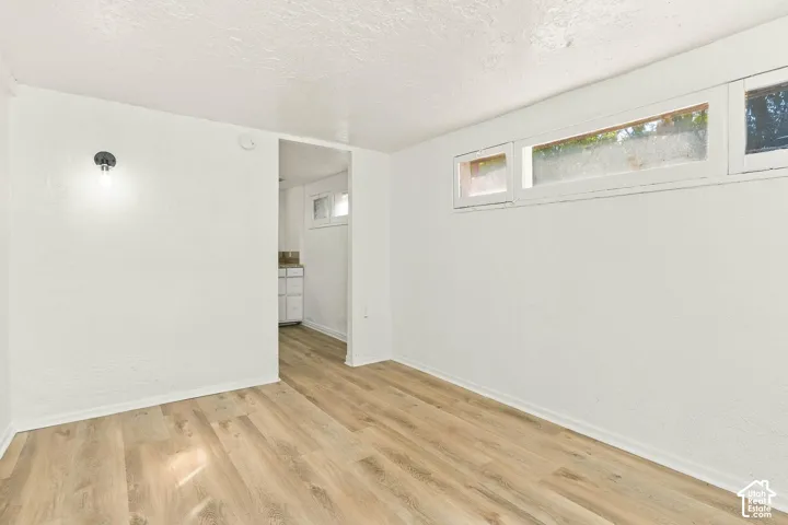 Interior space featuring wood-finish flooring, white walls, clerestory-style windows, and a wall-mounted light fixture