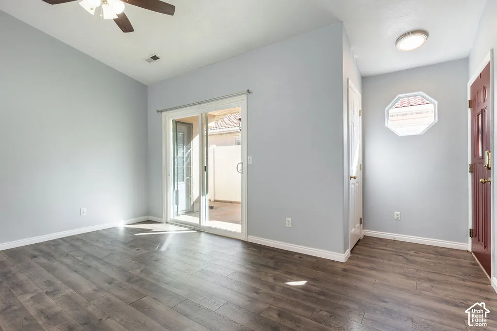Vaulted ceiling with a central paddle fan, wood-finish flooring, sliding glass door, and decorative octagonal window